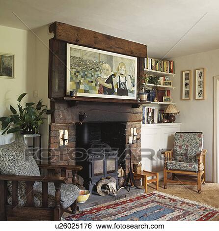 Stock Photograph - Picture above fireplace with black iron stove in cottage living room. Fotosearch