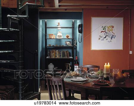 Picture - Picture on orange wall beside blue alcove in dining room with table set for dinner. Fotosearch