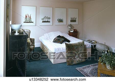 Pictures above bed with white duvet in sixties bedroom with large floor cushions View Large Photo Image Stock Image - Pictures above bed with white duvet in sixties bedroom with large floor cushions. Fotosearch