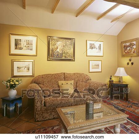 Stock Photo - Pictures above patterned sofa in yellow living room extension. Fotosearch