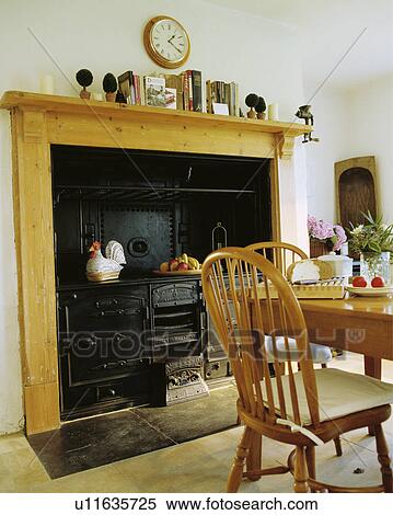 Pine mantelpiece with old black range stove in country dining room with Windsor chairs View Large Photo Image Stock Photography - Pine mantelpiece with old black range stove in country dining room with Windsor chairs. Fotosearch