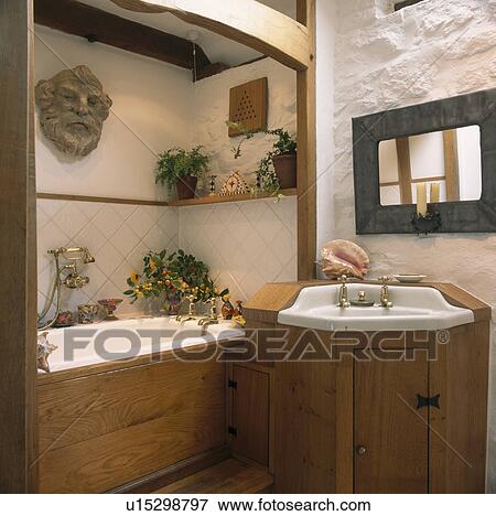 Pine panelling on bath and built-in basin in small cottage bathroom with painted white stone walls View Large Photo Image Stock Photo - Pine panelling on bath and built-in basin in small cottage bathroom with painted white stone walls. Fotosearch