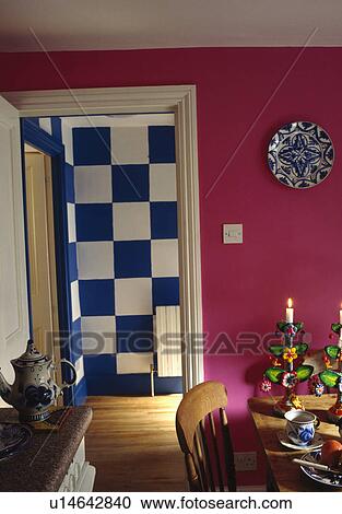 Pine table and chairs in bright pink dining room with doorway to large blue+white paint effect checks painted on wall View Large Photo Image Stock Image - Pine table and chairs in bright pink dining room with doorway to large blue+white paint effect checks painted on wall. Fotosearch