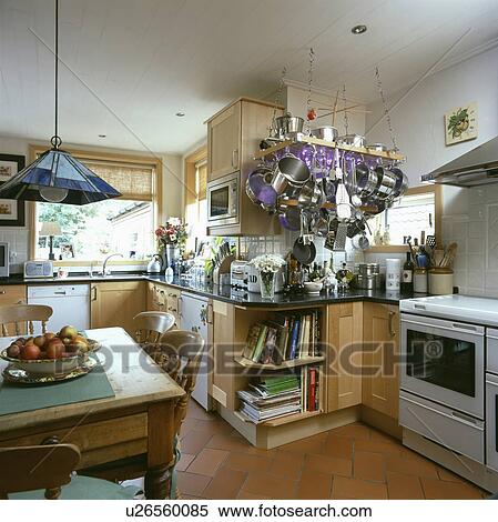 Pine table and chairs in white kitchen with stainless steel pans on rack suspended from the ceiling View Large Photo Image Stock Photography - Pine table and chairs in white kitchen with stainless steel pans on rack suspended from the ceiling. Fotosearch