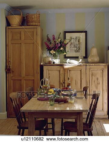 Pine table and chairs with tall pine cupboard and pine sideboard in dning room with blue+green striped wall View Large Photo Image Stock Image - Pine table and chairs with tall pine cupboard and pine sideboard in dning room with blue+green striped wall. Fotosearch