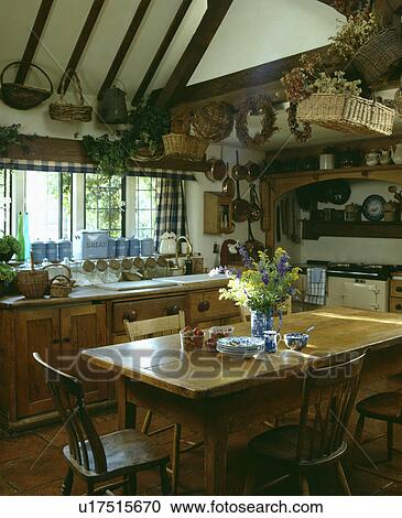 Pine table and old chairs in country kitchen with baskets on ceiling View Large Photo Image Stock Image - Pine table and old chairs in country kitchen with baskets on ceiling. Fotosearch