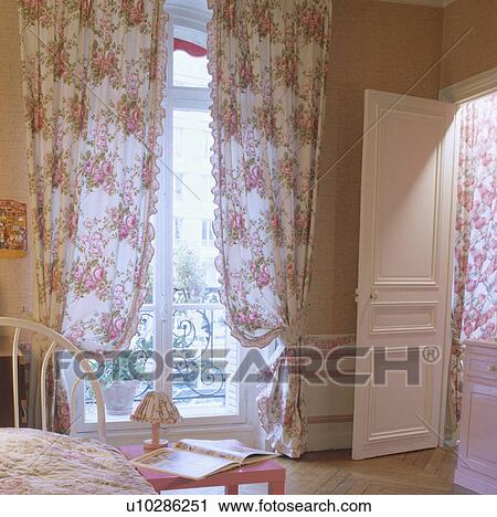 Pink rose-patterned curtains on French windows in apartment bedroom with white panelled door View Large Photo Image Stock Image - Pink rose-patterned curtains on French windows in apartment bedroom with white panelled door. Fotosearch