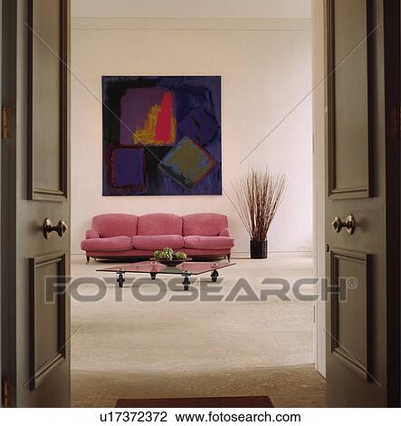 Stock Image - Pink sofa below abstract painting. Fotosearch