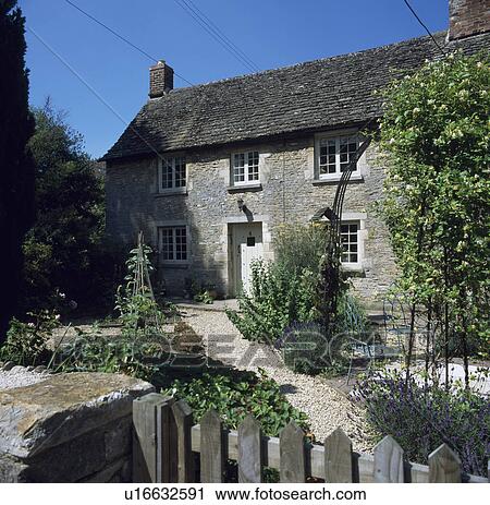 Stock Image - Plants in gravel garden in front of country cottage. Fotosearch