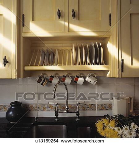 Plate rack in fitted cupboard above sink with chrome mixer tap View Large Photo Image Picture - Plate rack in fitted cupboard above sink with chrome mixer tap. Fotosearch