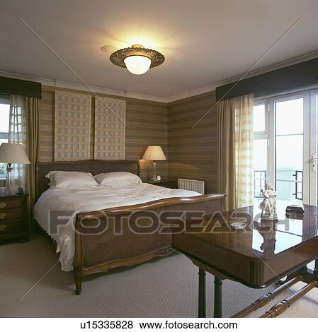 Polished wood antique bed with white linen in modern bedroom with glass doors to balcony View Large Photo Image Stock Photo - Polished wood antique bed with white linen in modern bedroom with glass doors to balcony. Fotosearch
