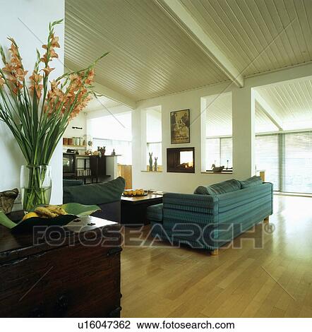 Stock Image - Polished wooden floor in modern white livingroom with blue sofa. Fotosearch