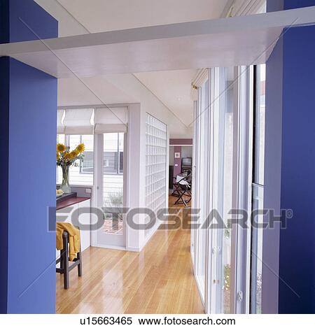 Stock Photography - Polished wooden flooring in modern white and blue hall with white blinds on windows. Fotosearch