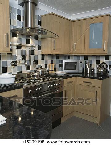 Range oven in modern pale wood kitchen with black grey and beige wall tiles View Large Photo Image Stock Photo - Range oven in modern pale wood kitchen with black grey and beige wall tiles. Fotosearch