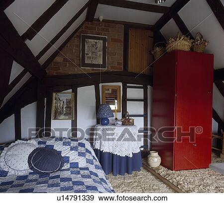 Red cupboard in beamed attic bedroom with blue+white patchwork quilt on bed View Large Photo Image Stock Photo - Red cupboard in beamed attic bedroom with blue+white patchwork quilt on bed. Fotosearch