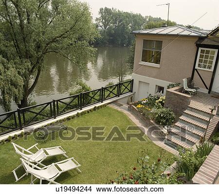 River at the bottom of country garden with chaiselongue on lawn View Large Photo Image Picture - River at the bottom of country garden with chaiselongue on lawn. Fotosearch