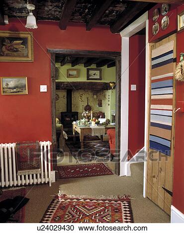 Rugs on radiator and pine door in red cottage hall with view of living room through open door View Large Photo Image Stock Image - Rugs on radiator and pine door in red cottage hall with view of living room through open door. Fotosearch