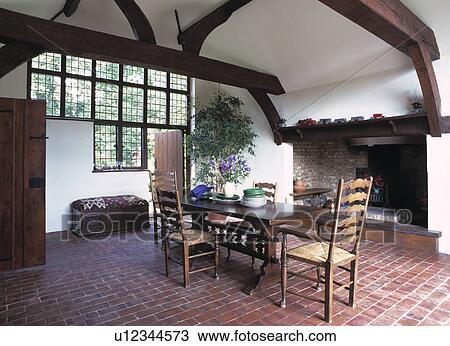 Rush-seated ladderback chairs and Arts+Crafts table in white country dining room with tiled floor and large fireplace View Large Photo Image Stock Image - Rush-seated ladderback chairs and Arts+Crafts table in white country dining room with tiled floor and large fireplace. Fotosearch
