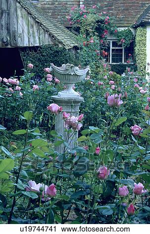 Stock Image - Sculpture in flowering borders in country garden in summer. Fotosearch