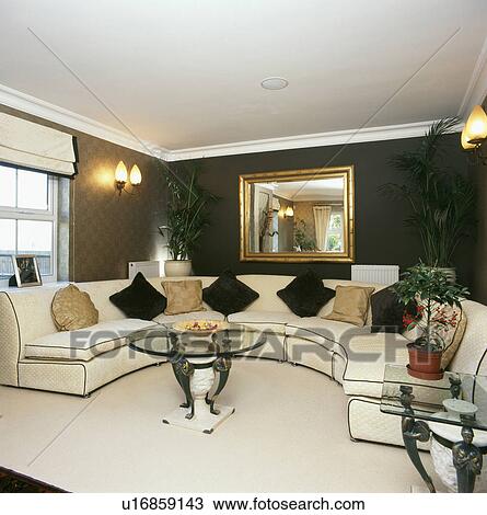 Semi-circular cream sofa and circular glass-topped table in brown living room with cream carpet  View Large Photo Image Stock Image - Semi-circular cream sofa and circular glass-topped table in brown living room with cream carpet . Fotosearch