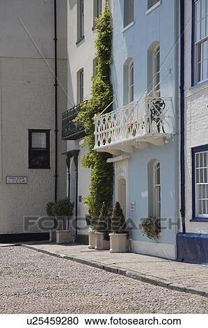 Side view of pastel blue traditional townhouse with white wrought-iron balcony View Large Photo Image Stock Image - Side view of pastel blue traditional townhouse with white wrought-iron balcony. Fotosearch