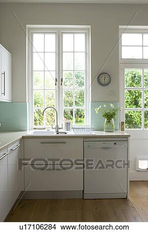 Picture - Sink and dishwasher below window in modern white kitchen. Fotosearch