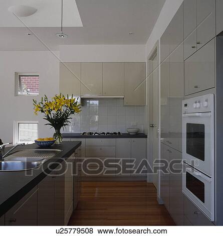 Stock Photo - Sink in island unit in large modern grey and white kitchen . Fotosearch