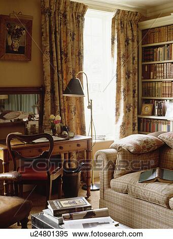 Small pine desk and brass standard lamp beside window with patterned curtains in country living room View Large Photo Image Stock Photography - Small pine desk and brass standard lamp beside window with patterned curtains in country living room. Fotosearch