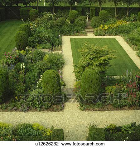 Stock Image - Small rectangular lawn with gravel paths edged with mixed borders with structure provided by clipped yew and infilled with perennials -valarian, loosestrife delphiniumsand lady's mantle.. Fotosearch