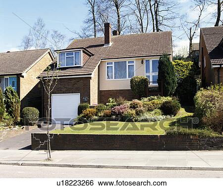 Stock Photograph - Small single-storey house with integral garage below dormer window. Fotosearch