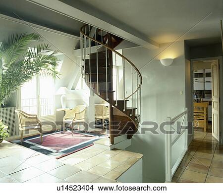 Spiral staircase and wicker chairs on tiled floor in openplan landing View Large Photo Image Picture - Spiral staircase and wicker chairs on tiled floor in openplan landing . Fotosearch
