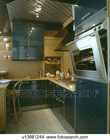 Stainless steel eye-level oven in compact modern kitchen with halogen lighting View Large Photo Image Picture - Stainless steel eye-level oven in compact modern kitchen with halogen lighting. Fotosearch