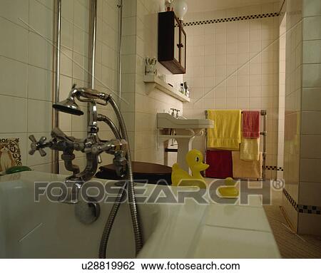 Stainless steel taps and showerhead on bath with yellow plastic ducks on the side in traditional white tiled bathroom View Large Photo Image Stock Image - Stainless steel taps and showerhead on bath with yellow plastic ducks on the side in traditional white tiled bathroom. Fotosearch