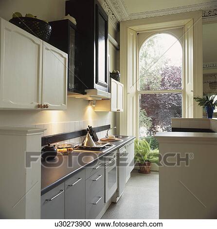 Stainless steel worktops in grey galley kitchen with tall sash window View Large Photo Image Stock Image - Stainless steel worktops in grey galley kitchen with tall sash window. Fotosearch