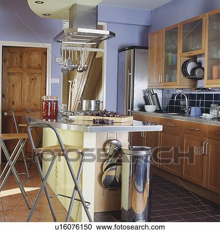 Steel waste bin below breakfast bar on island unit with metal and wood stools in blue country kitchen View Large Photo Image Stock Image - Steel waste bin below breakfast bar on island unit with metal and wood stools in blue country kitchen. Fotosearch