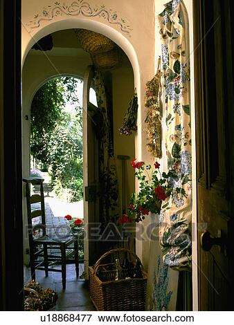 Stock Photo - Stencil over arch in hall with front door open to the garden and wooden chair in the doorway. Fotosearch