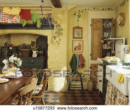 Stencilled leaf and grape pattern on painted cream brick walls in cottage kitchen with pine table and chairs View Large Photo Image Stock Image - Stencilled leaf and grape pattern on painted cream brick walls in cottage kitchen with pine table and chairs. Fotosearch