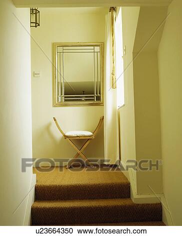 Steps up to wooden stool below square mirror in small cream hall with sisal carpet View Large Photo Image Stock Image - Steps up to wooden stool below square mirror in small cream hall with sisal carpet. Fotosearch