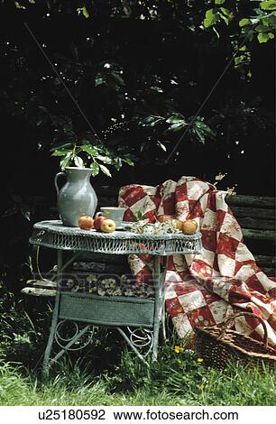 Stock Image - Still-Life of blue wicker table and red+white patchwork fabric. Fotosearch