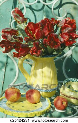 Stock Image - Still-Life of red tulips in jellow jug. Fotosearch