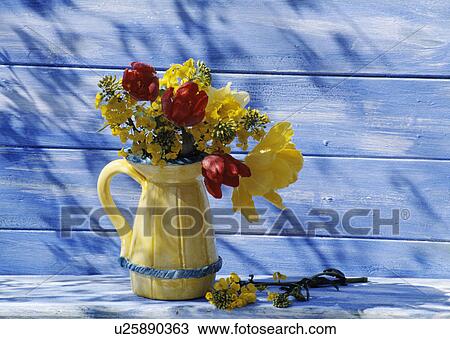 Stock Image - Still-Life of yellow and red spring flowers in yellow jug. Fotosearch