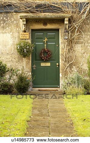 Stock Image - Stone path to green front door with Christmas wreath on English country house. Fotosearch