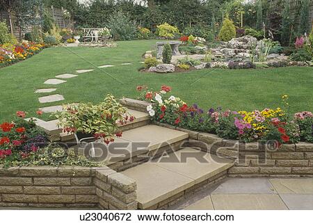Stock Image - Stone steps to lawn in suburban garden in summer. Fotosearch