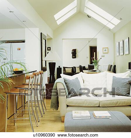 Stock Image - Stools at breakfast bar in modern openplan living room extension with white sofa. Fotosearch