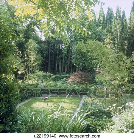 Stock Image - Sunken lawn surrounded by trees in summer country garden. Fotosearch