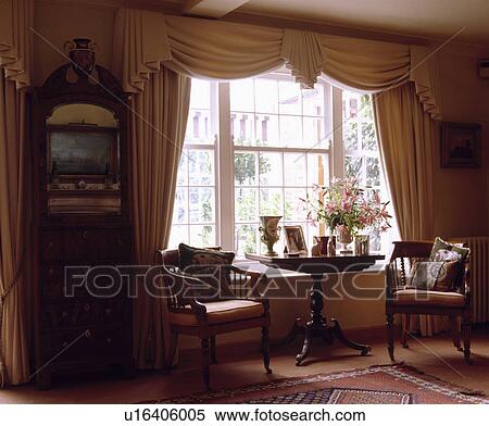Stock Photography - Swagged and tailed curtains in traditional living room. Fotosearch