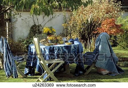 Stock Photo - Table and chairs on lawn in country garden in summer. Fotosearch
