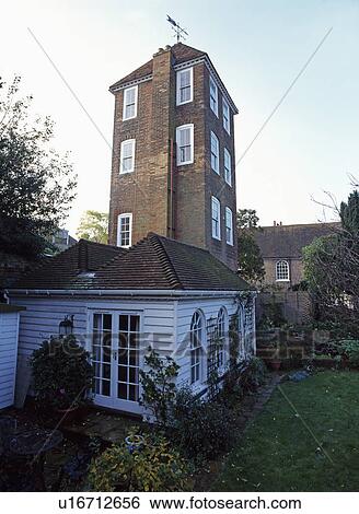 Stock Photograph - Tall tower converted into house with single-storey white timbered extension. Fotosearch