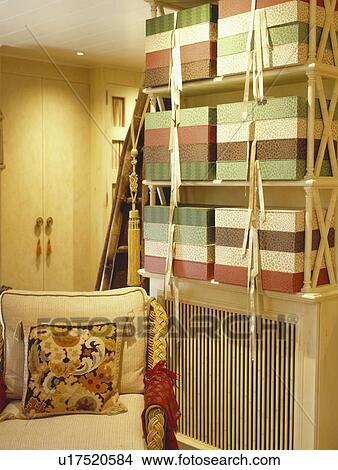 Picture - Tapestry cushion on cream sofa in study area of livingroom with striped storage boxes on shelf unit. Fotosearch