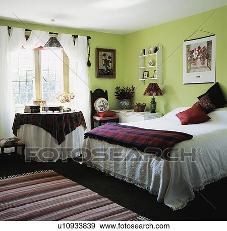 Tartan throw on bed in lime-green bedrool with black and white cloths on circular table in front of window View Large Photo Image Stock Photo - Tartan throw on bed in lime-green bedrool with black and white cloths on circular table in front of window. Fotosearch